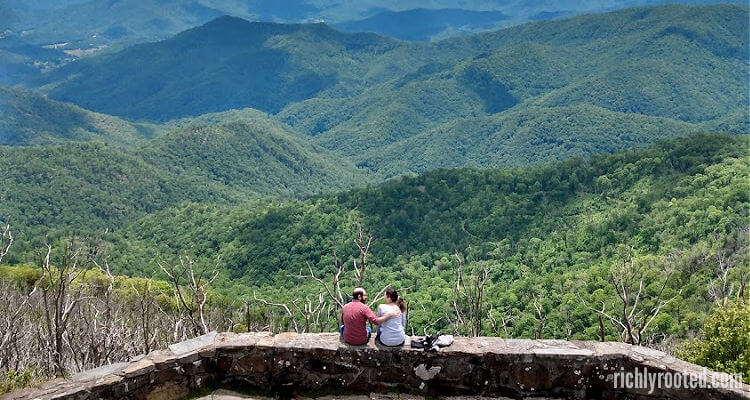 Couple sitting on a stone wall overlooking the Appalachian Mountain range.